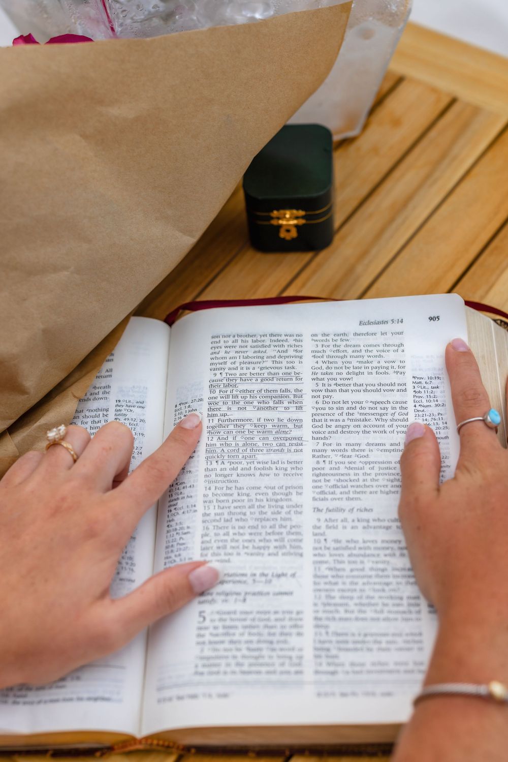 Close-up of hands turning pages in an open book on a wooden table.