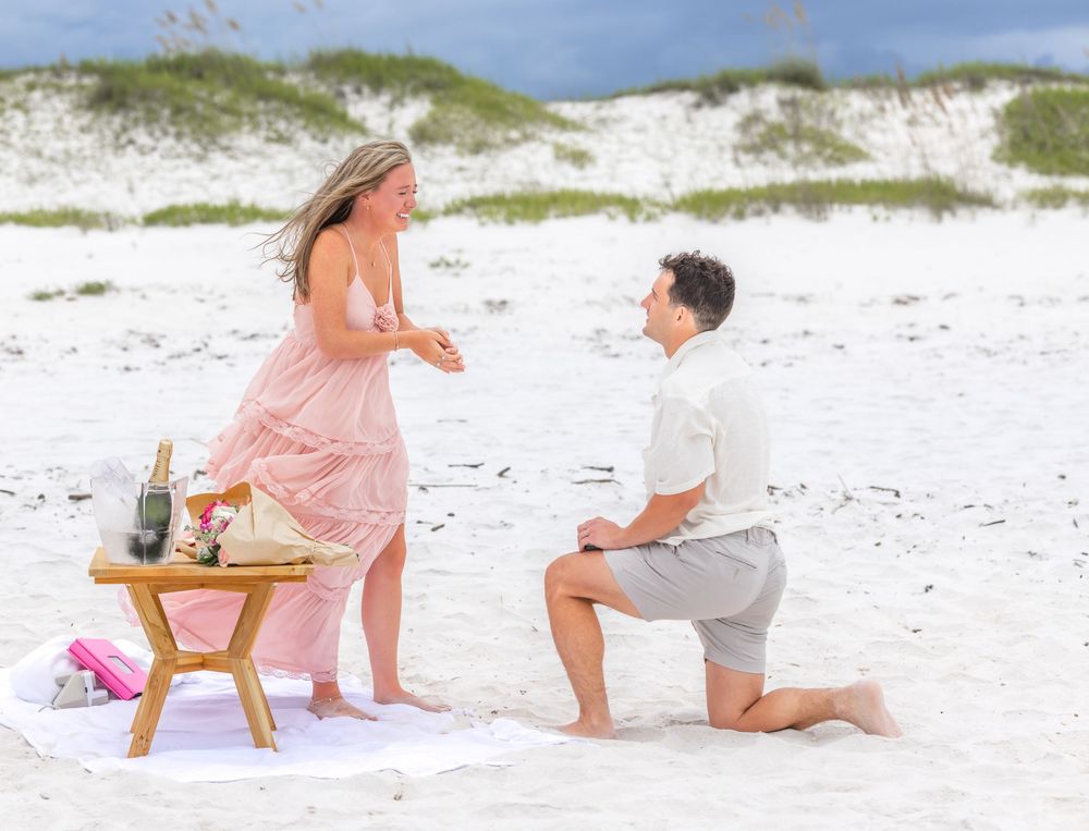 A romantic beach proposal scene with couple on white sand.