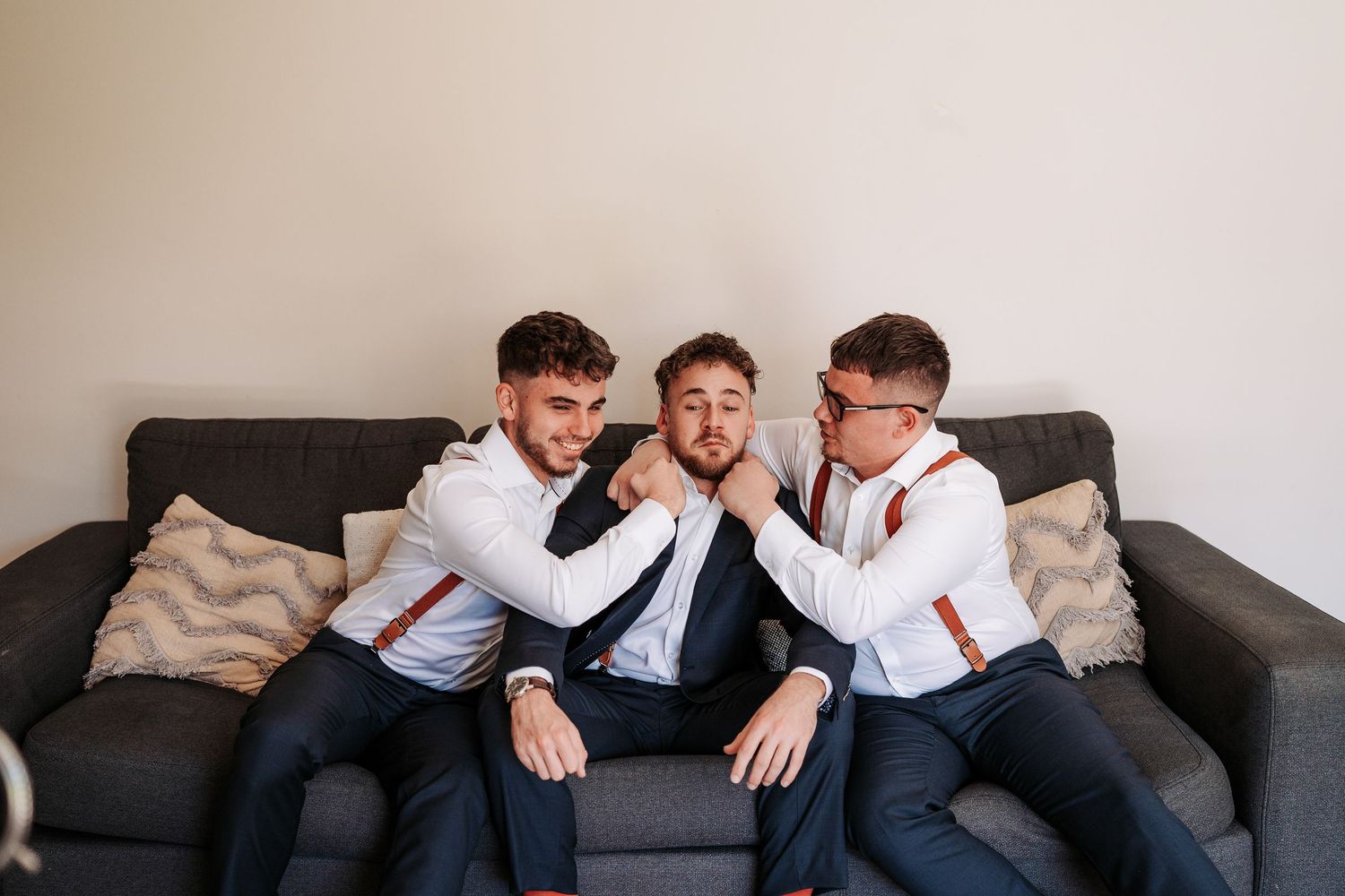 Friends share laughter and camaraderie while relaxing on a comfortable gray couch together in a casual setting.