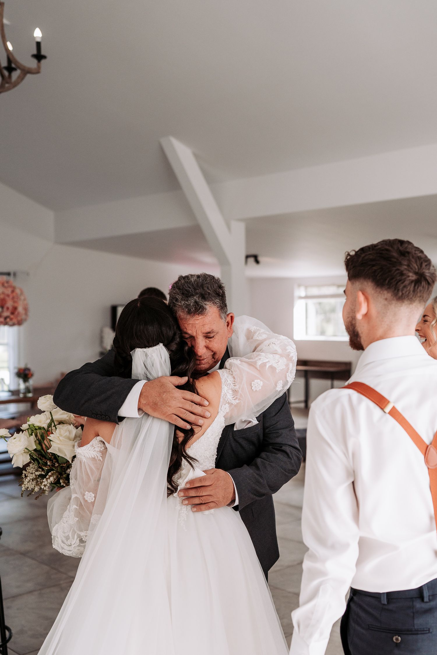 Wedding party greets couple in a sun-filled room for an emotional first look moment.