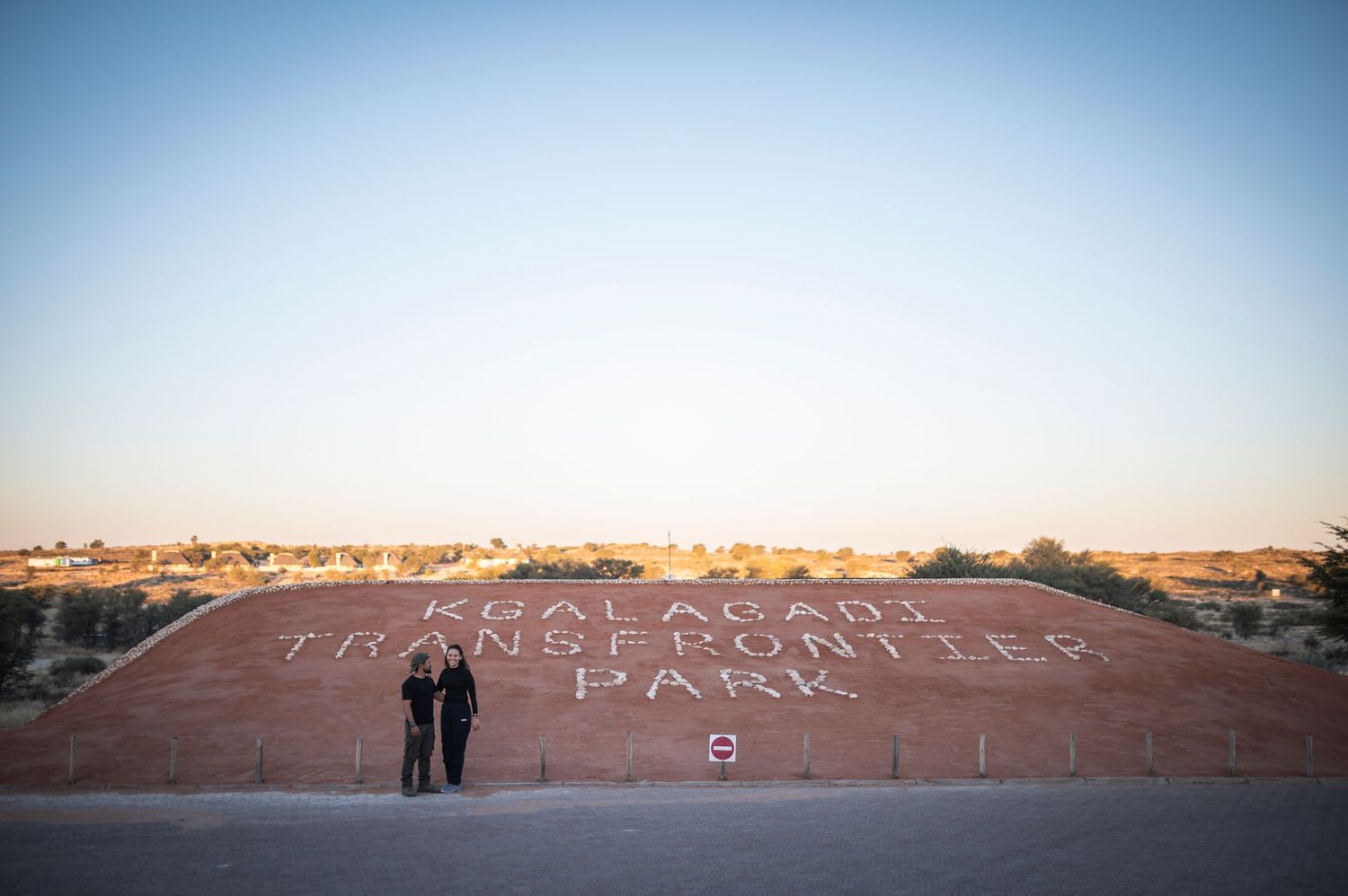 Two people stand together on red rock formation at sunset at Lambert Park in Alice Springs, Northern Territory.