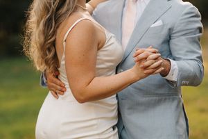 A couple shares a romantic dance together outdoors on their wedding day in a beautiful natural setting.