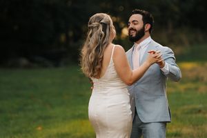 A romantic couple shares a dance moment in a sunlit field during golden hour.