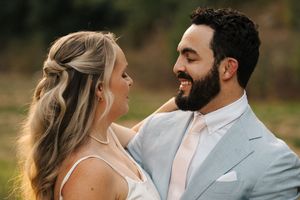 A close-up outdoor portrait of a couple laughing together in formal wedding attire.