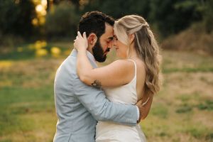 Romantic couple embraces intimately in a golden sunlit field during sunset.