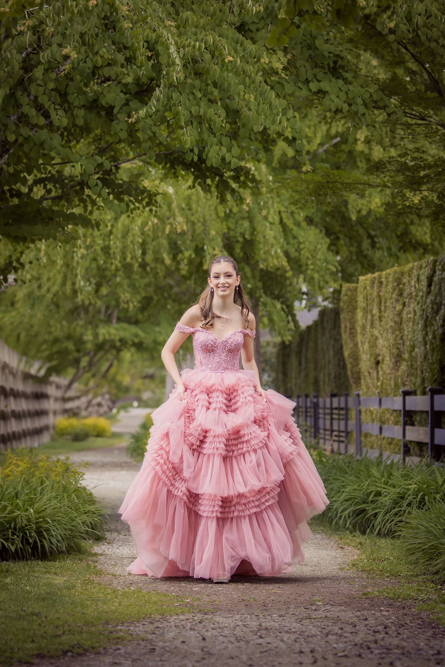 Ethereal scene of a person in a flowing pink layered tulle gown posing gracefully in a wildflower meadow at sunset. grad portraits