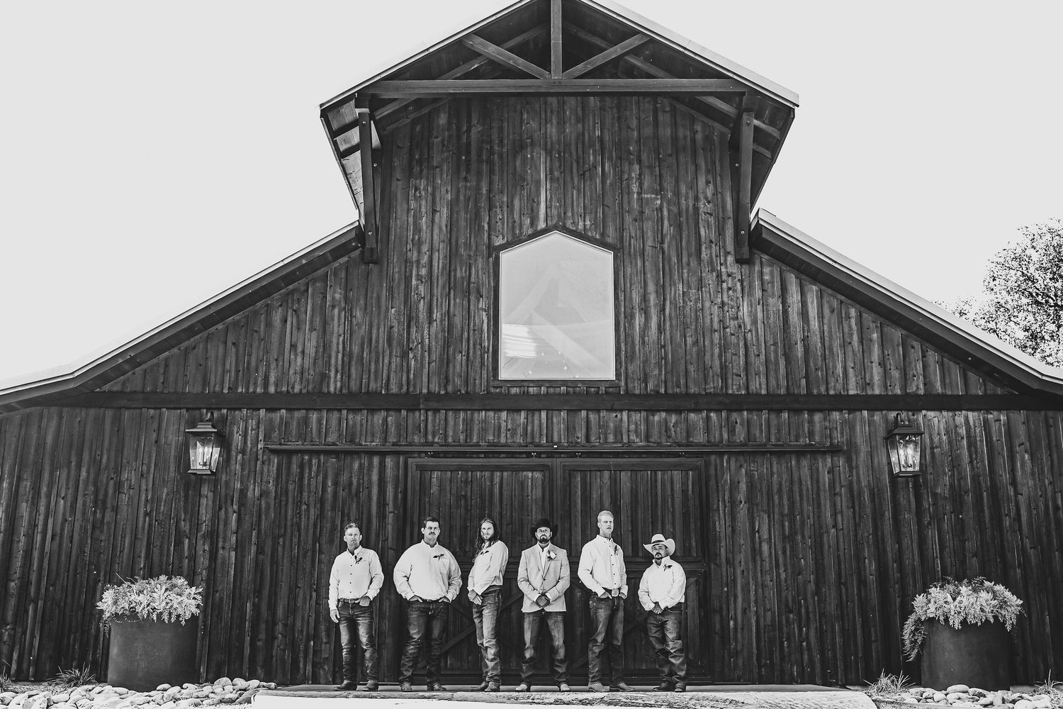 Rustic Texas wedding groomsmen photo in front of Whispering Oaks barn