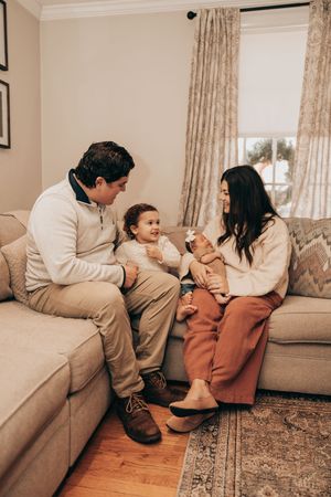 A series of progressive images showing playful interaction on a couch in a living room with beige decor and hardwood floors.