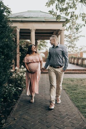 A couple walking together on a brick patio pathway during a romantic outdoor photo session.