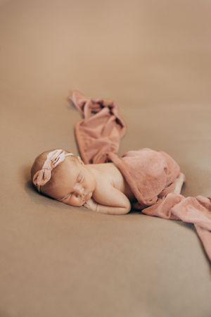 A series of minimalist photographs showing a sleeping newborn baby on a neutral beige background.