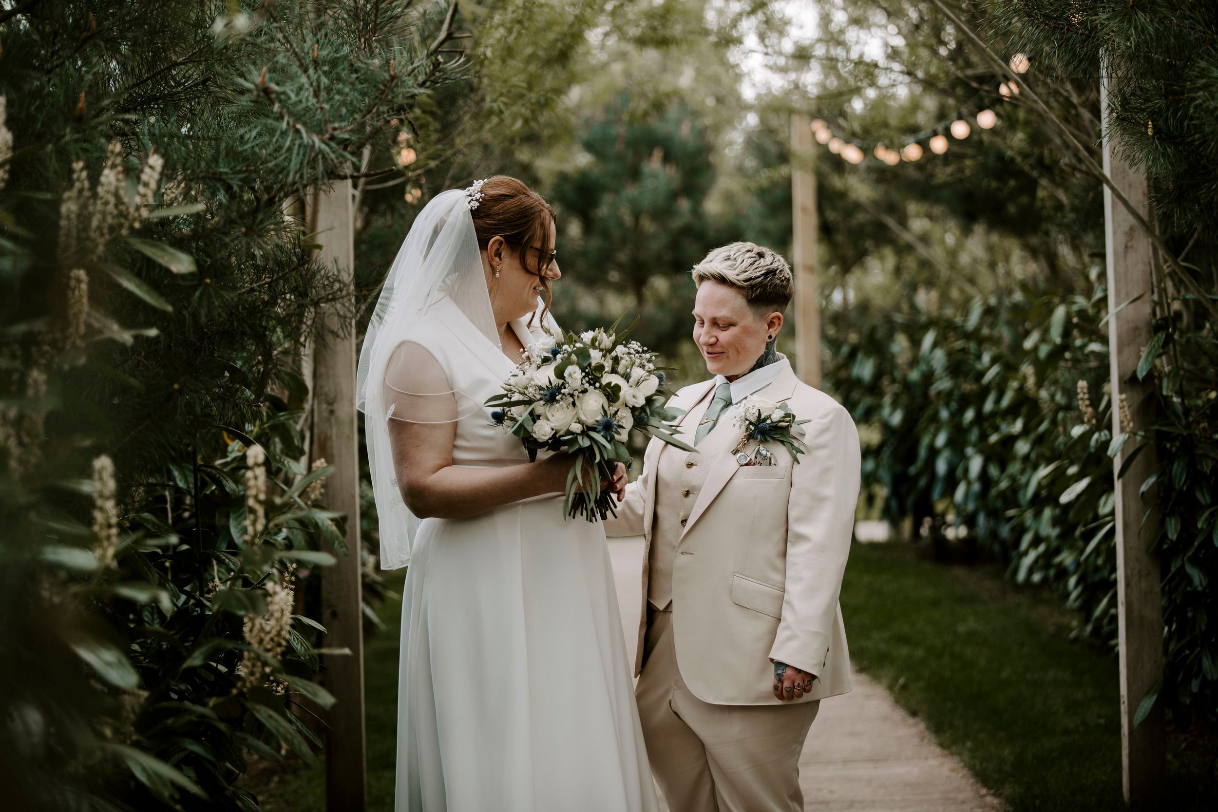 A romantic newlywed couple shares an intimate moment under string lights during their outdoor garden wedding ceremony.