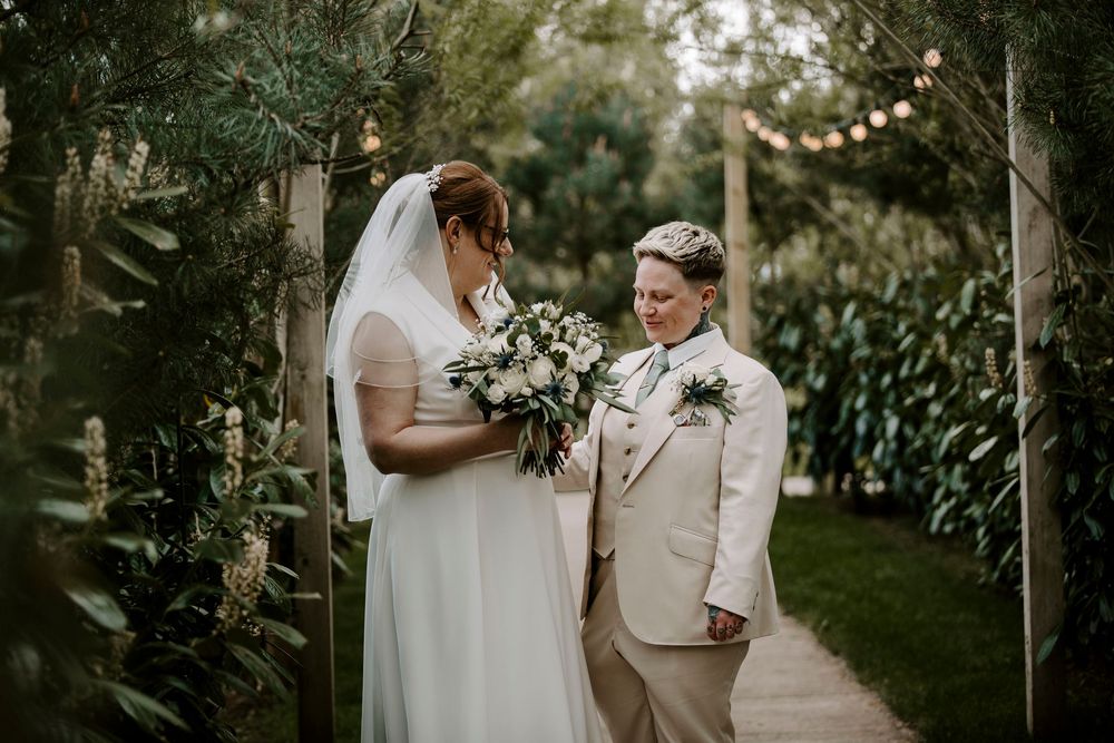 A romantic newlywed couple shares an intimate moment under string lights during their outdoor garden wedding ceremony.