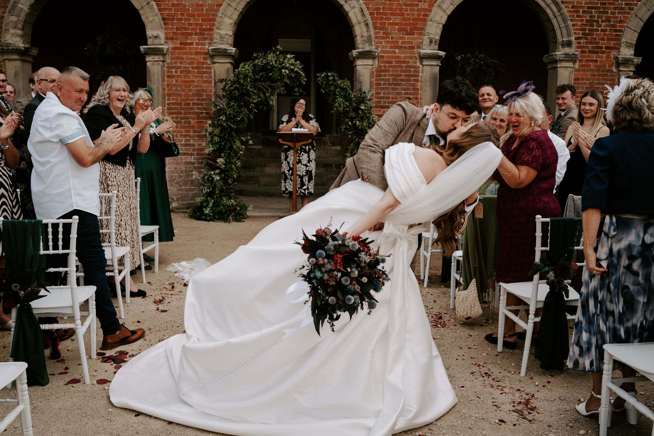 An elegant couple dances with dramatic flair during their wedding reception at a rustic brick venue.