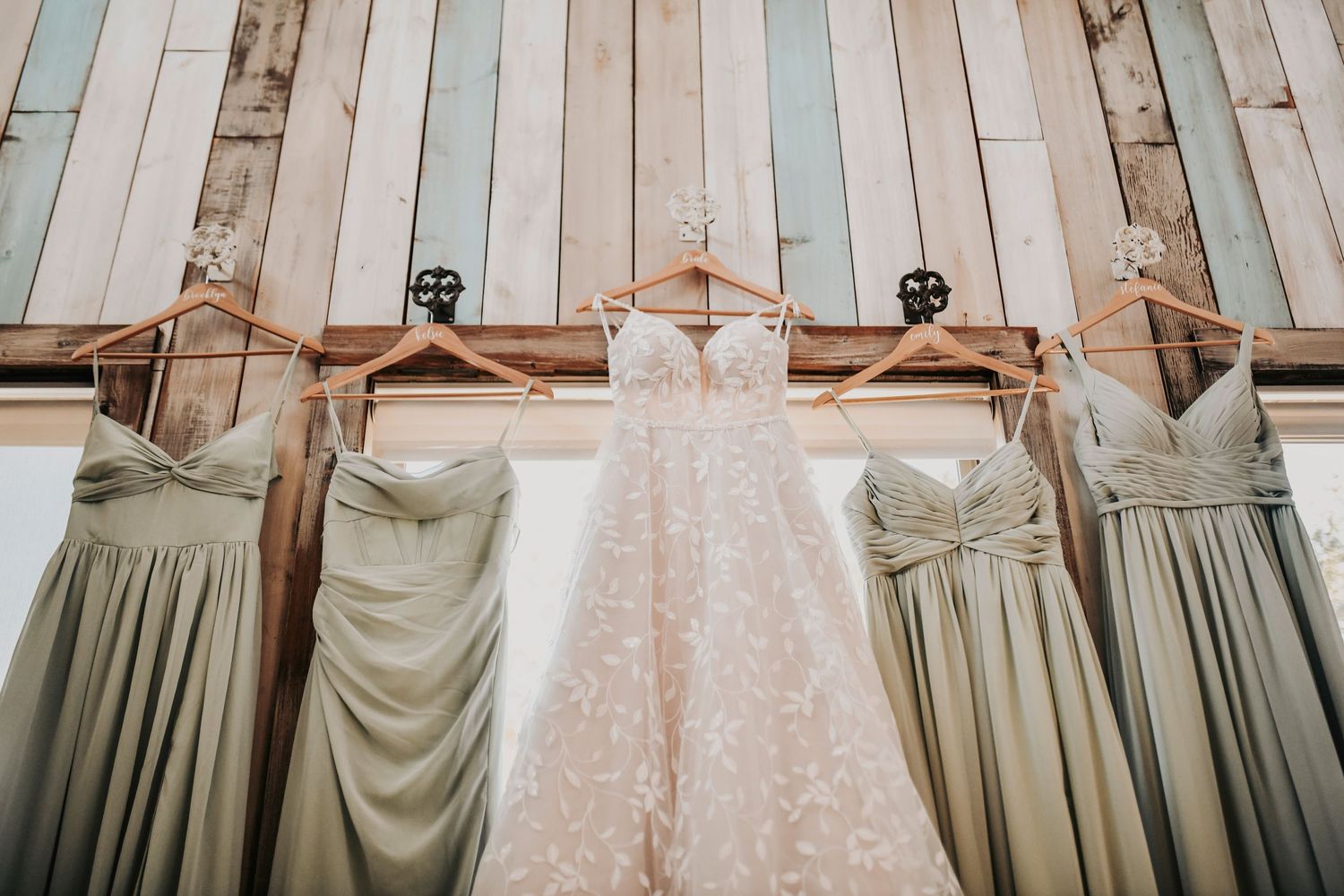 bridal gown and bridesmaids gowns hang in a shiplap wall in the bridal suite