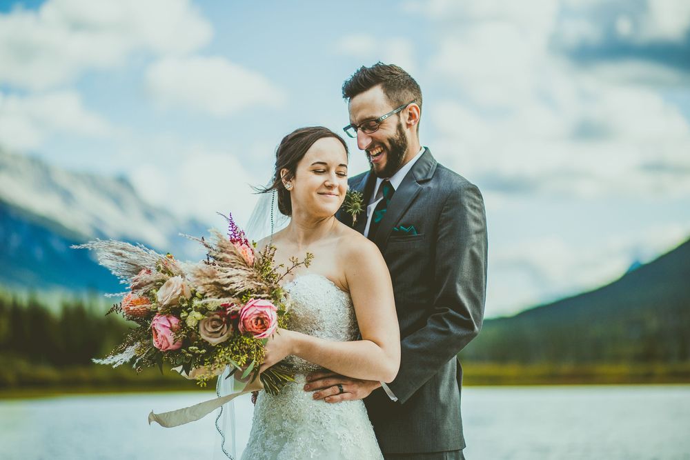A couple poses in formal attire against stunning mountain and lake scenery during their outdoor wedding Banff Micro Wedding Photographer