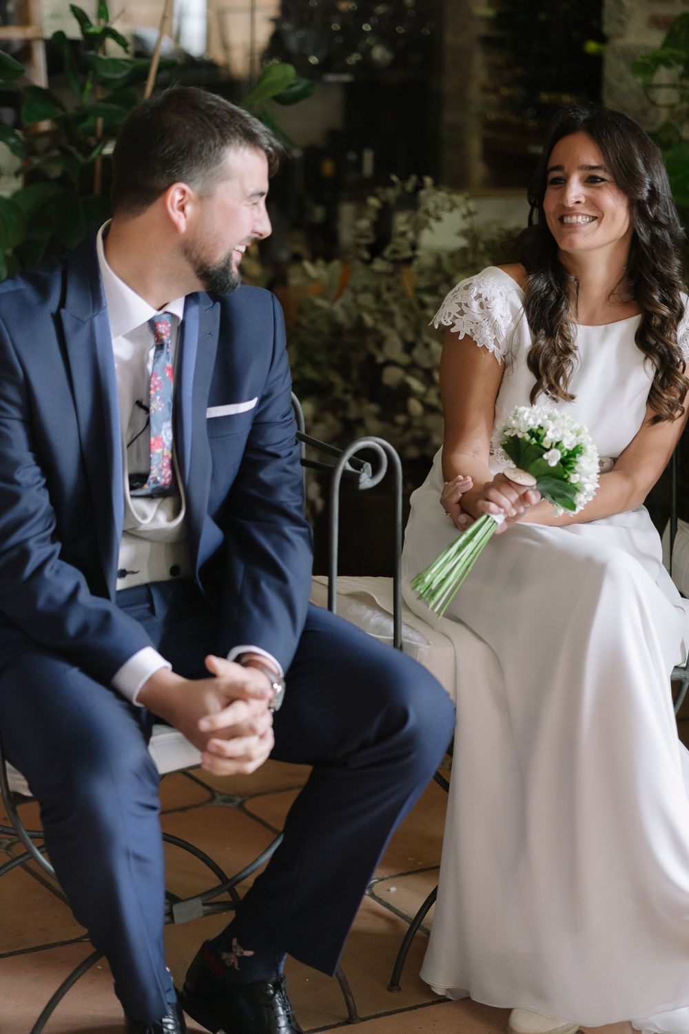 A couple sharing a joyful moment while seated in an outdoor garden setting.