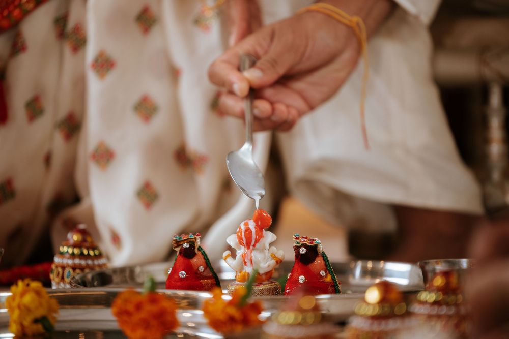 Someone serves traditional Indian wedding food during a ceremony with orange and gold decorative elements.