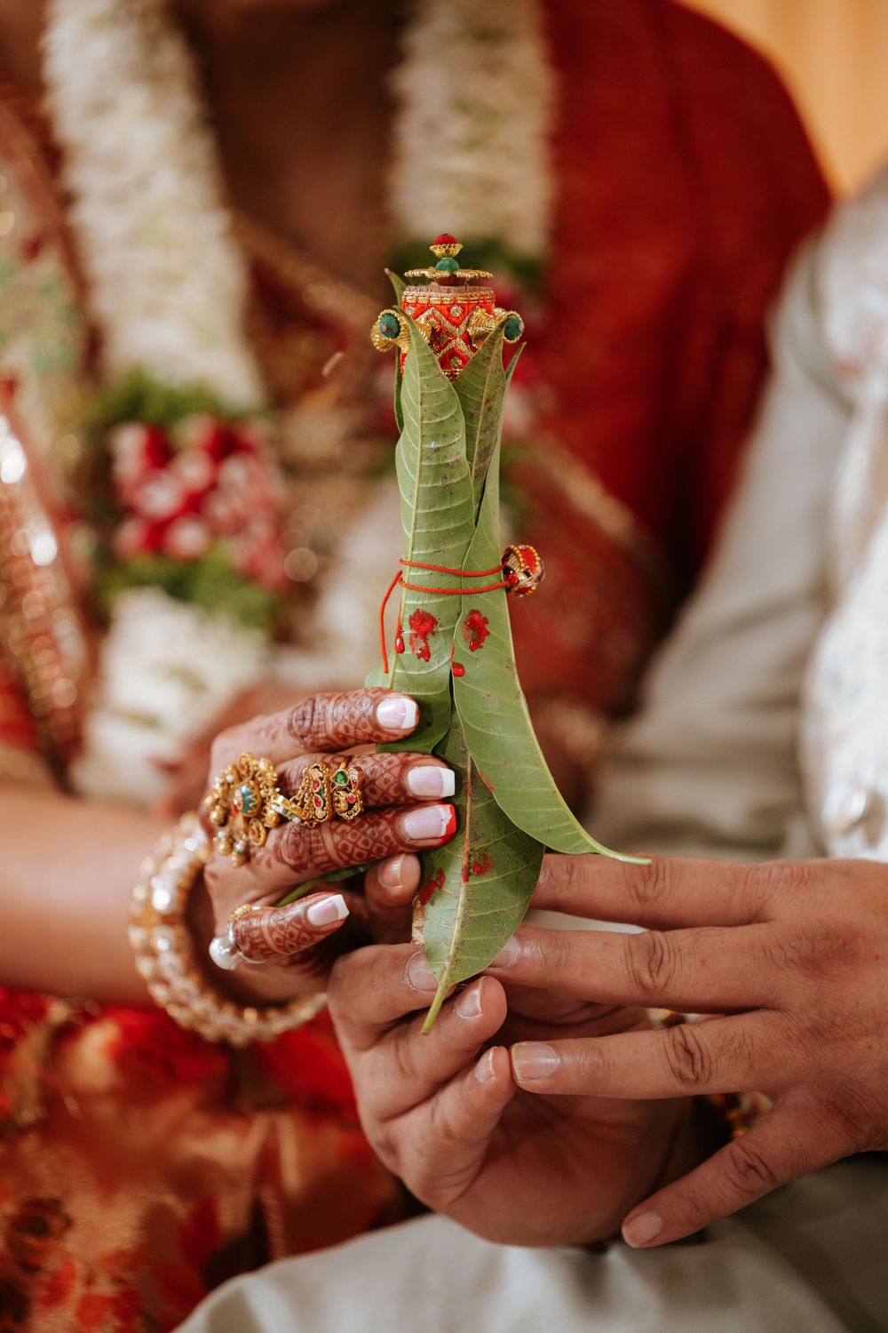 Hands exchanging traditional betel leaf and areca nut offerings during an Indian wedding ceremony ritual.