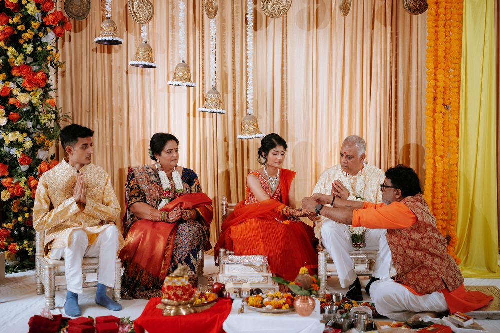 Traditional Indian wedding ceremony with vibrant red and gold decorations and festive floral arrangements displayed.