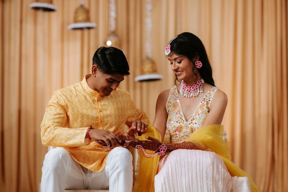 Women in fancy attire participate in a traditional haldi ceremony with yellow turmeric paste during pre-wedding celebrations.