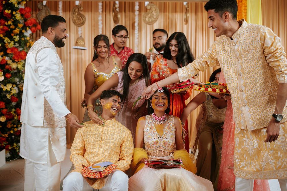 Traditional Indian wedding ceremony participants performing sacred rituals with flowers and decorative elements.