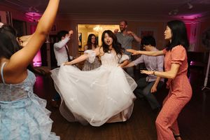 Wedding guests dancing and twirling on the colorful dance floor at a reception with pink uplighting.