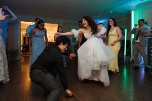 Dancers on a party floor during a wedding reception with someone in a white dress twirling energetically.