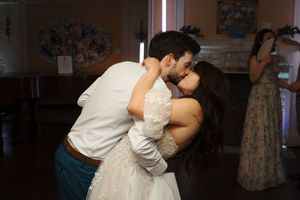A couple shares a romantic kiss during their dance at a wedding reception.