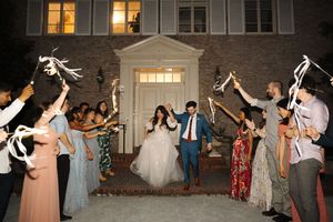Wedding party guests dance joyfully with sparklers at an evening outdoor reception celebration.