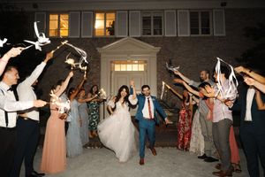 Wedding guests dance in a synchronized line during an outdoor evening reception celebration.