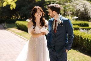 A happy couple shares a romantic moment outdoors in a garden setting wearing formal wedding attire.