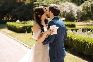 A couple dancing and embracing outdoors in a manicured garden with sunlit greenery.