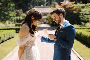 A couple dancing together outdoors in wedding attire, surrounded by lush greenery and natural sunlight.