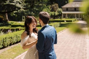 Joyful wedding couple dancing and laughing together on a brick pathway surrounded by lush gardens.