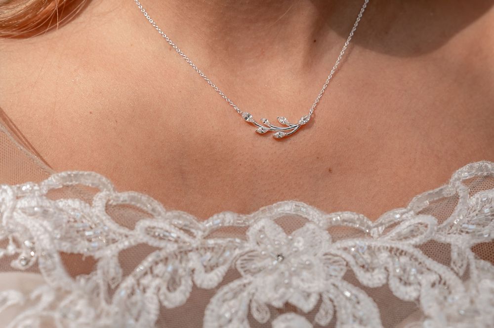 Delicate lace trim detail along the neckline of a white wedding dress with pearl accents.