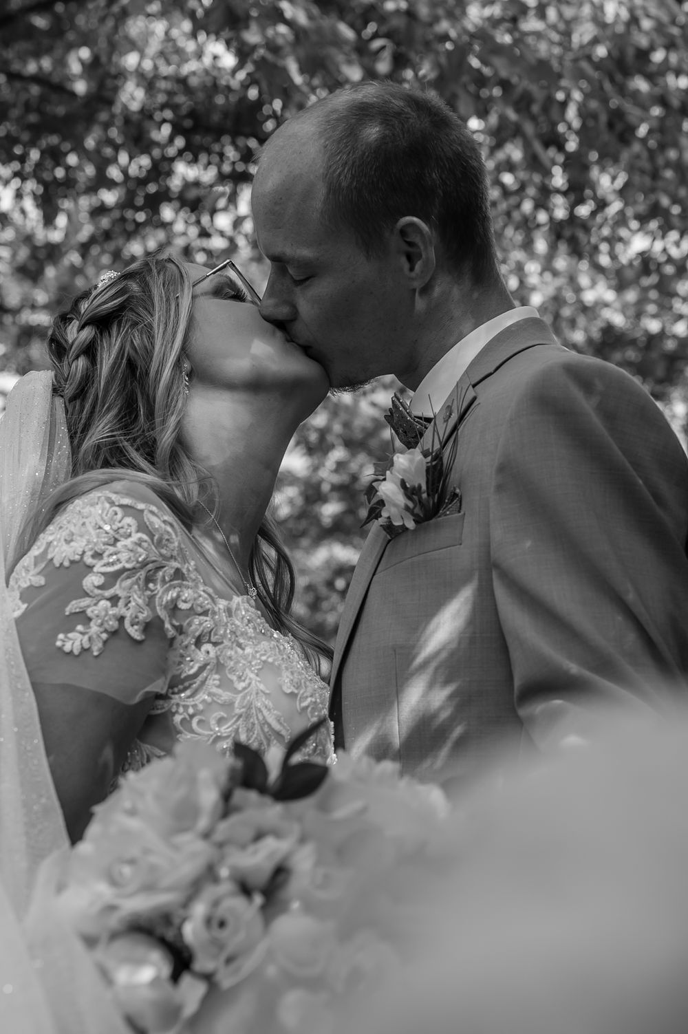 A romantic black and white wedding photo series showing tender moments between a bride and groom outdoors.