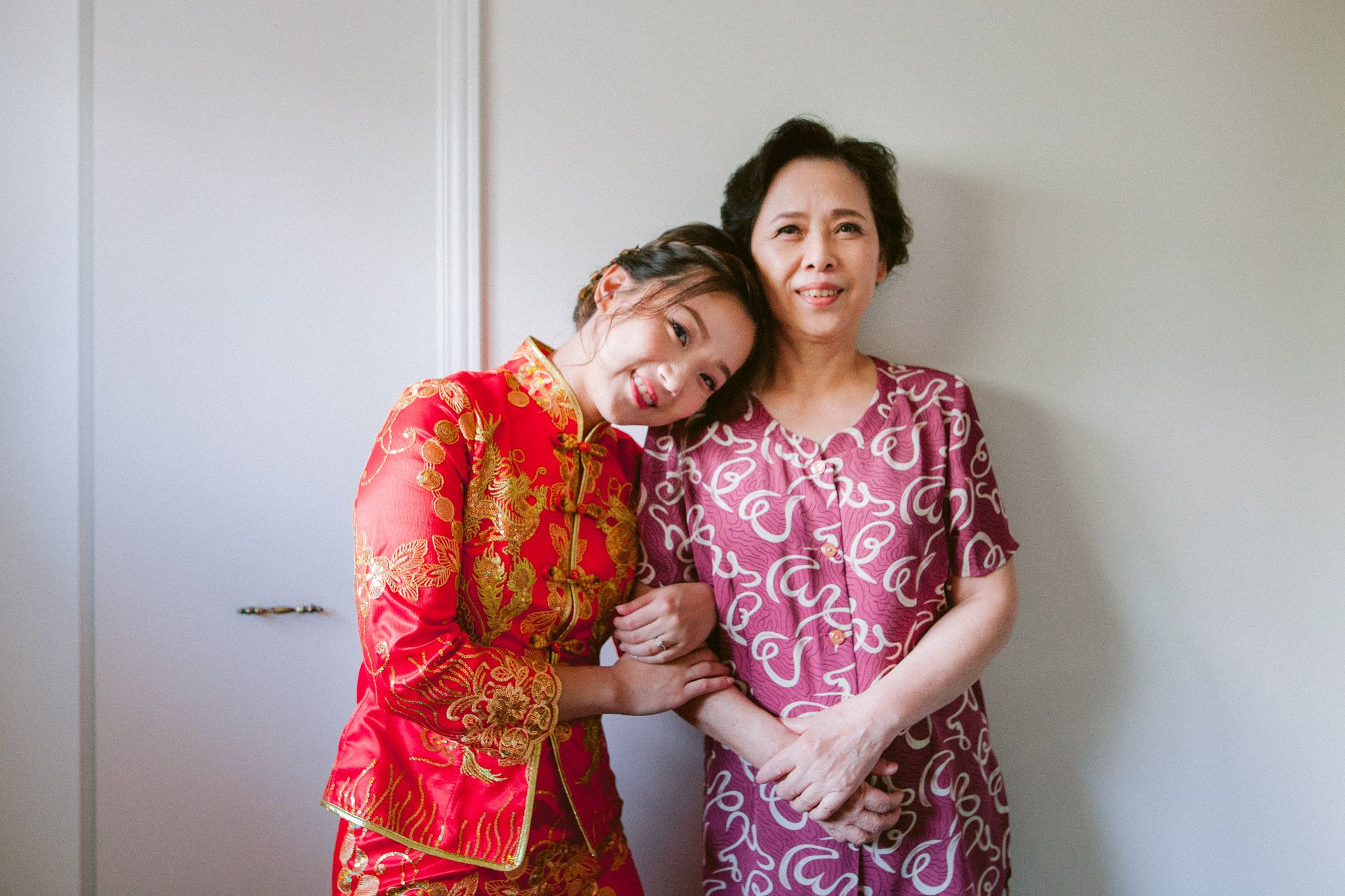 Two people in red and pink traditional outfits embracing and posing for photos during a celebration.