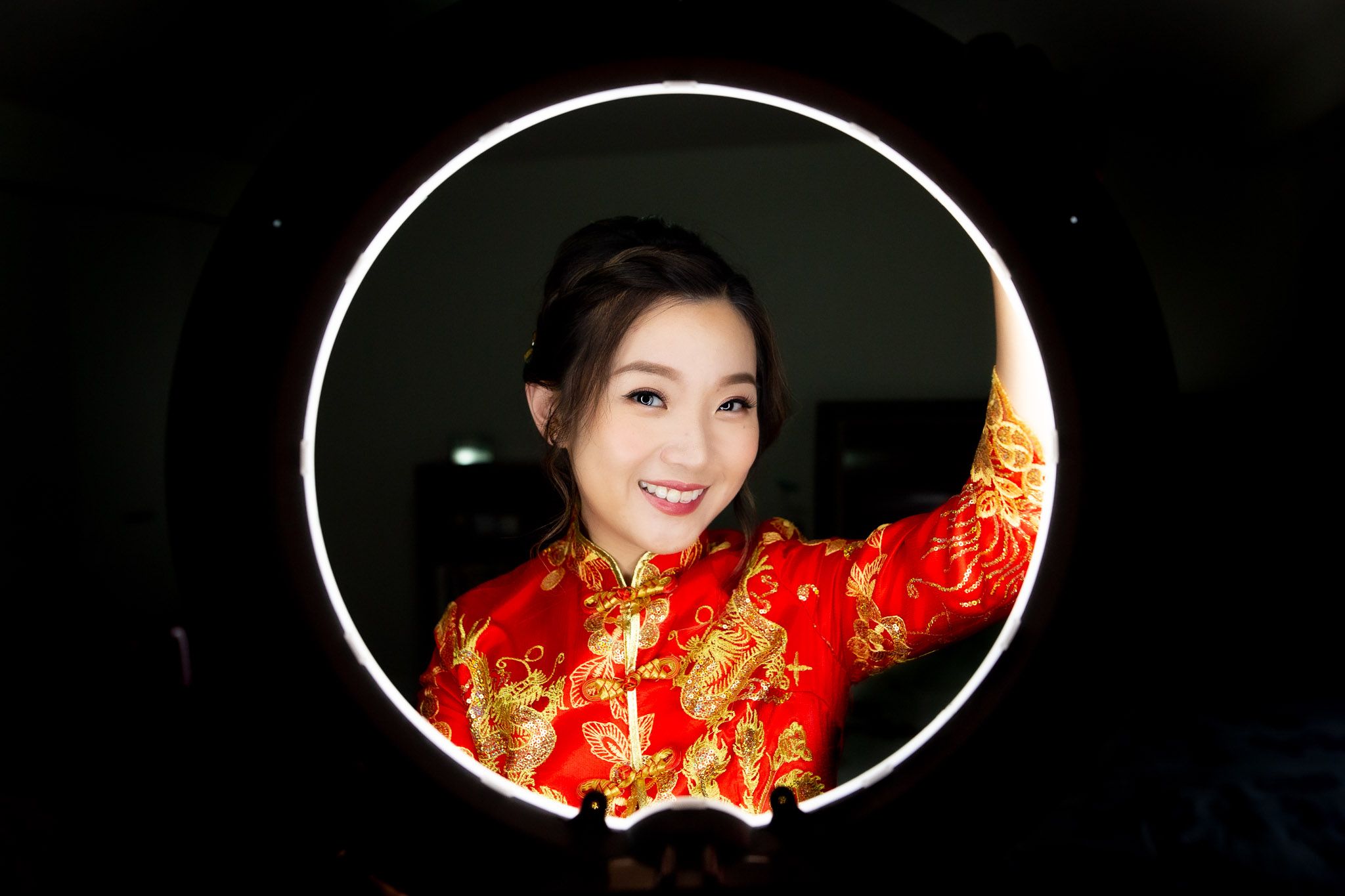 Traditional Chinese wedding attire in red and gold captured in dramatic lighting.