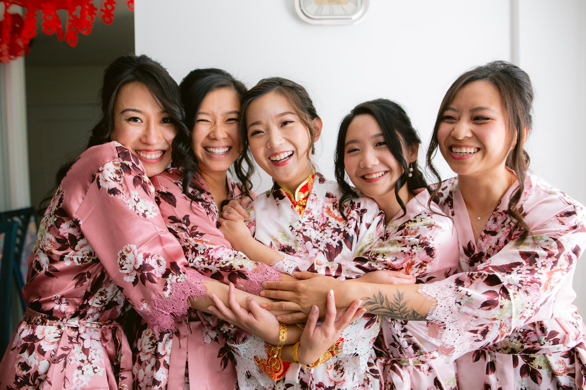 Several people in coordinated pink floral robes share laughter and conversation at a gathering.