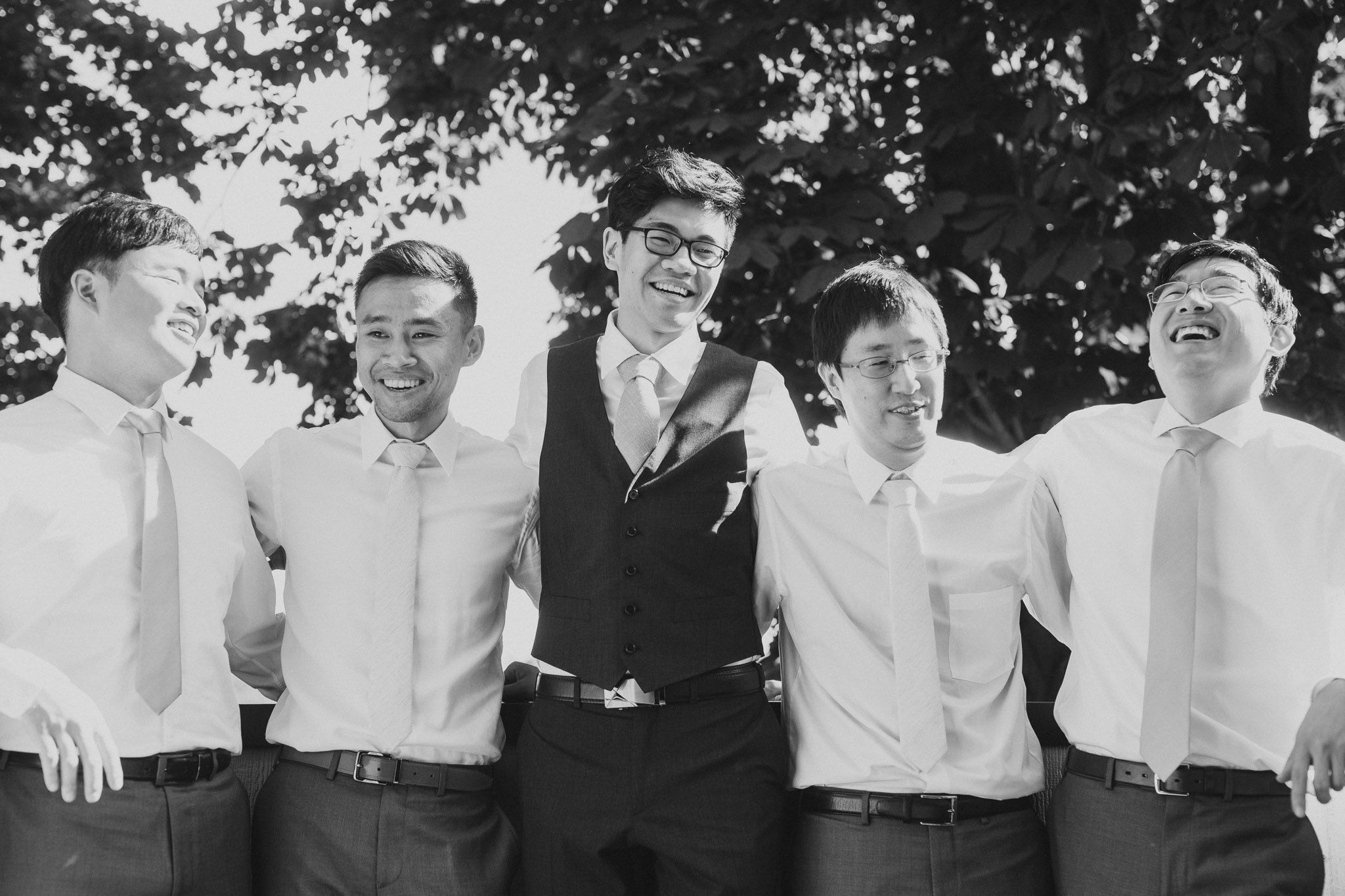 A series of black and white photos showing people laughing and smiling together in a casual outdoor setting.