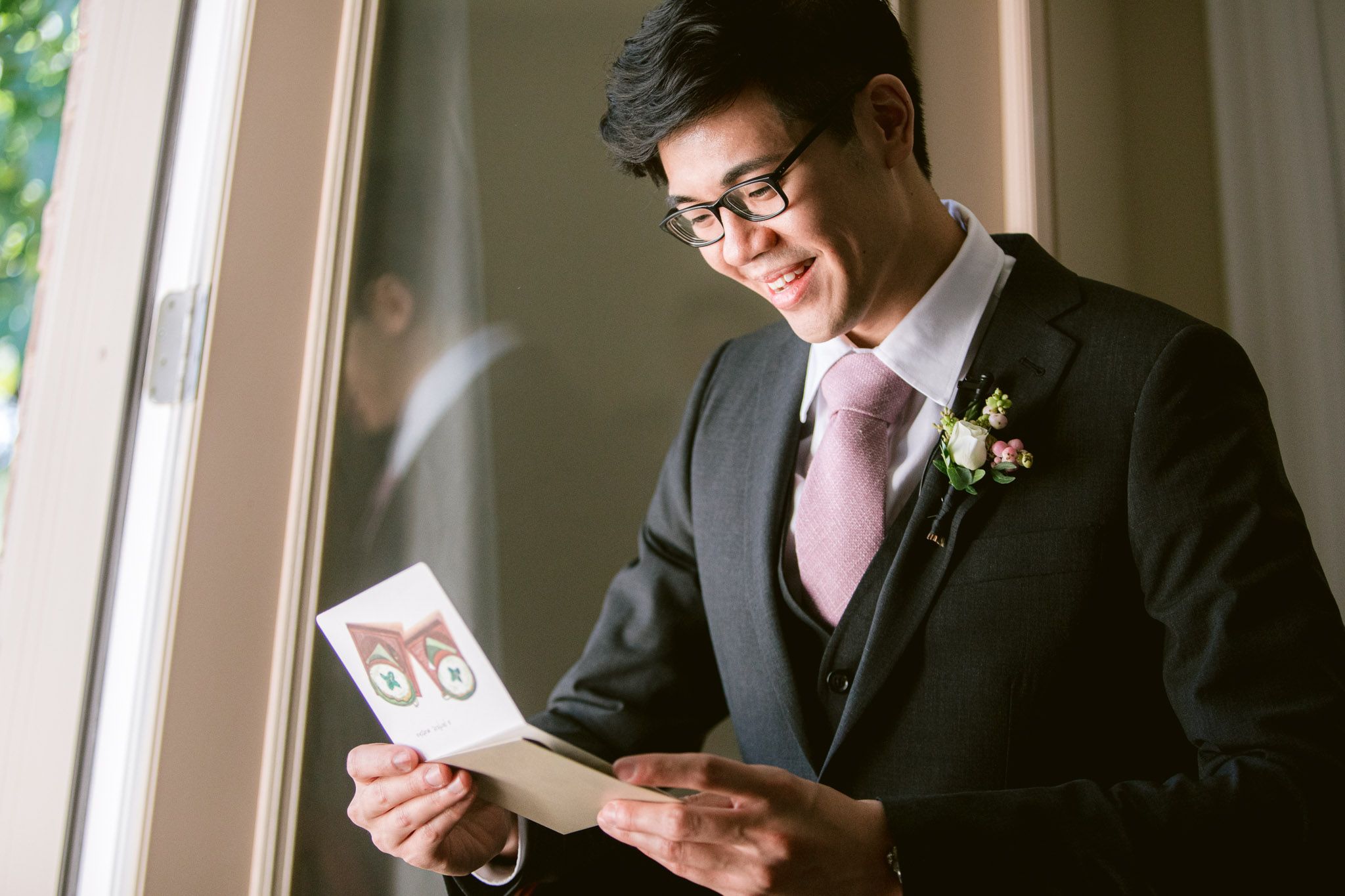 Wedding guests in formal attire use their phones during an indoor reception event.