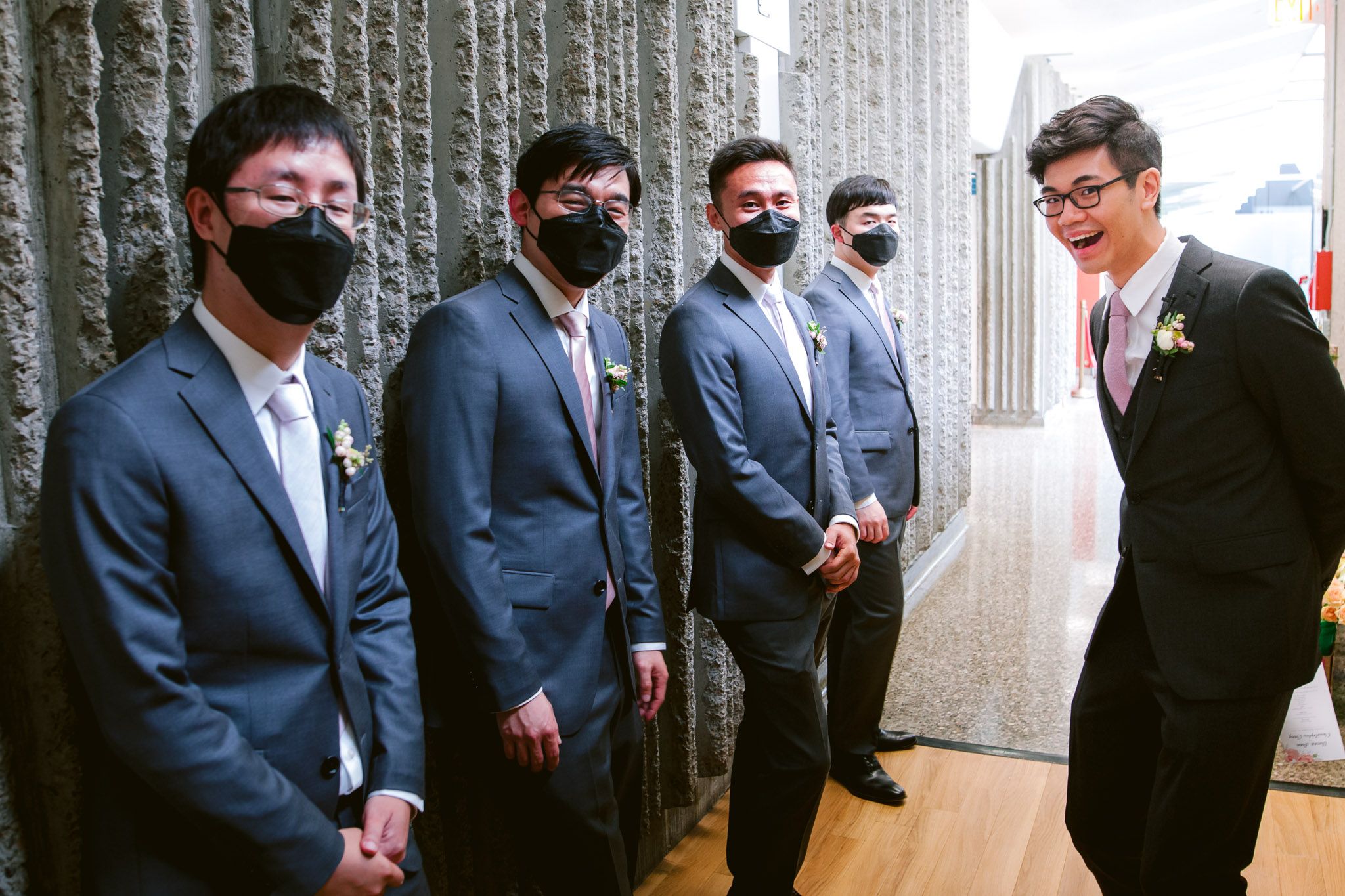 Group of people in formal suits standing together at an indoor venue.
