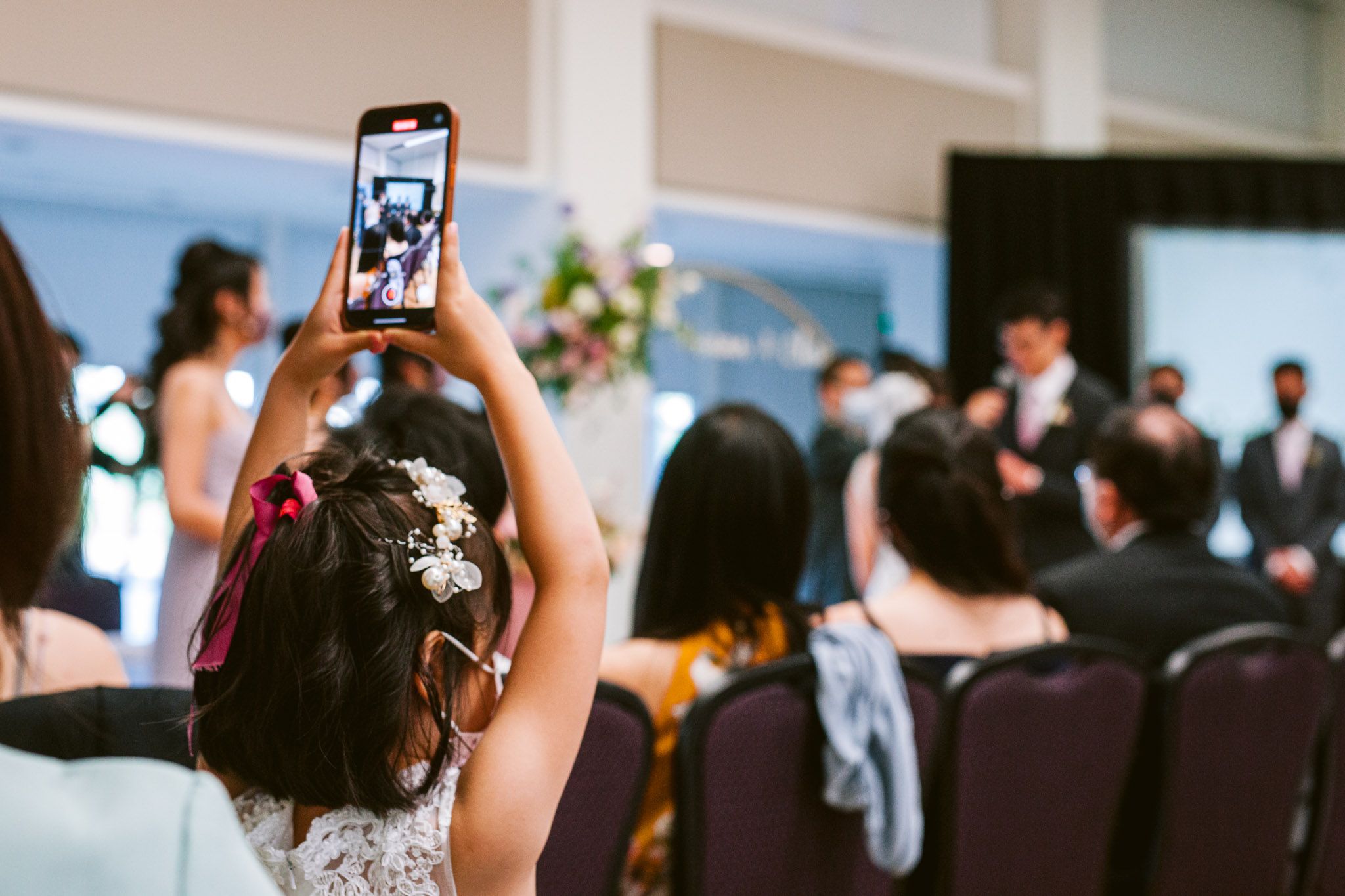 Wedding guests using phones to capture moments during a reception ceremony.