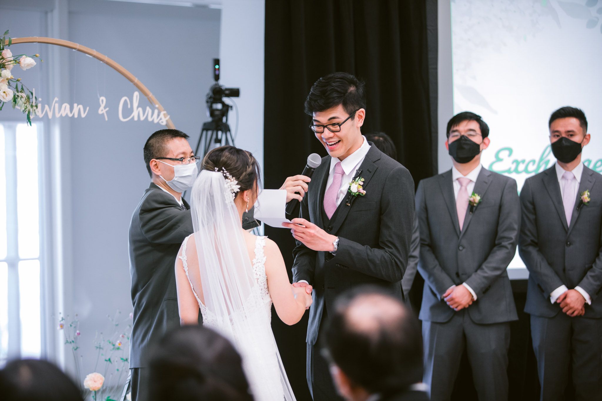 Wedding party members in formal attire gathered for group photos indoors.