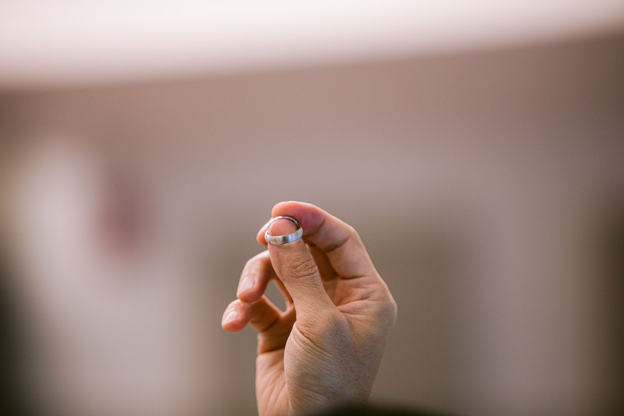 A close-up shot of hands holding a small white pill or medication tablet against a blurred background.