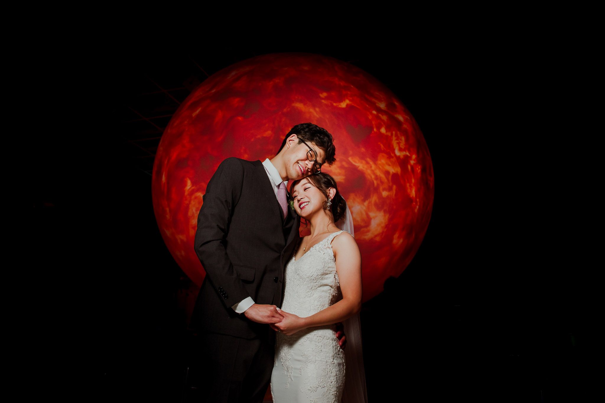 Romantic silhouettes against a dramatic red backdrop during an evening wedding photoshoot.