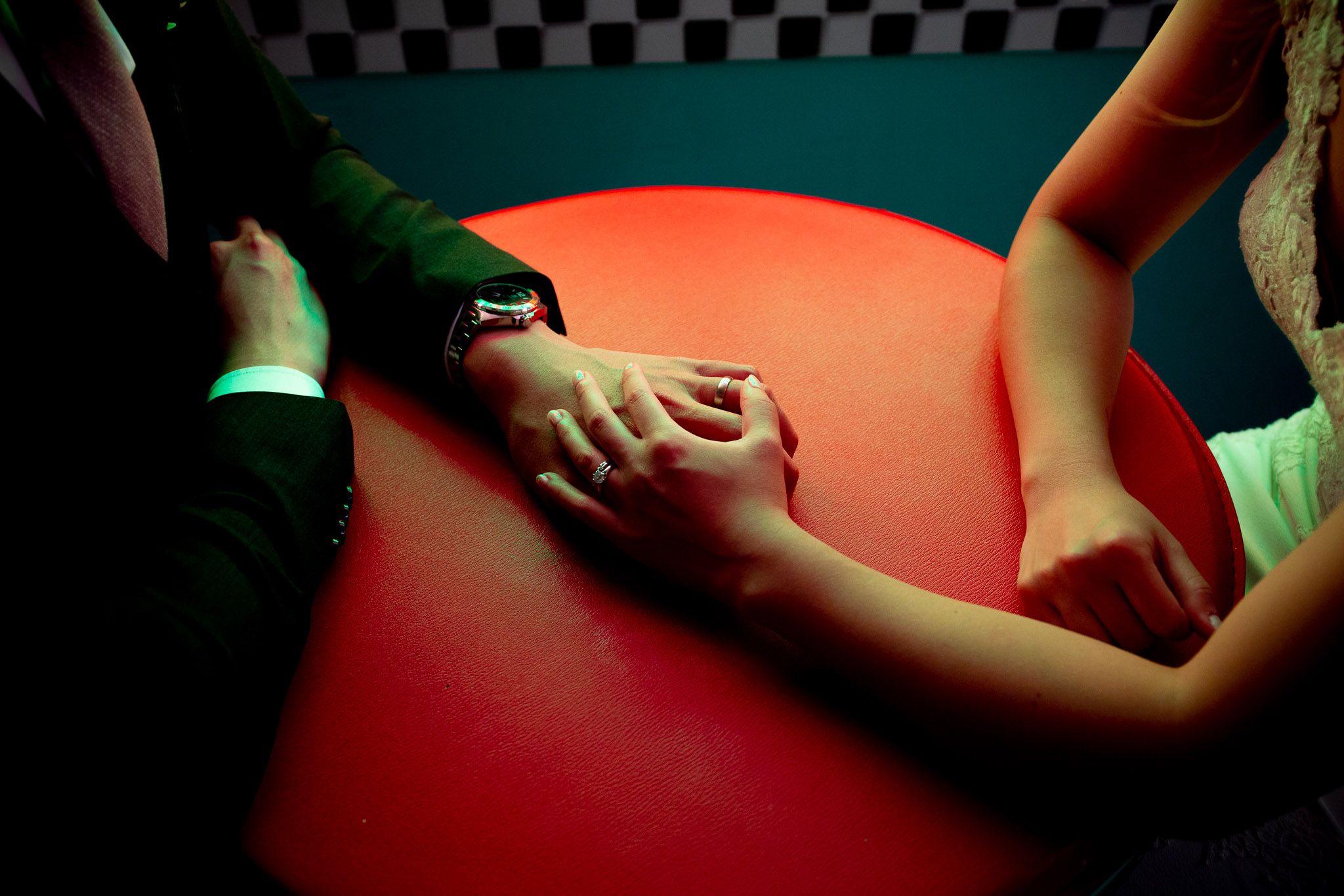Several people dance together on a dimly lit dance floor with red and green lighting.