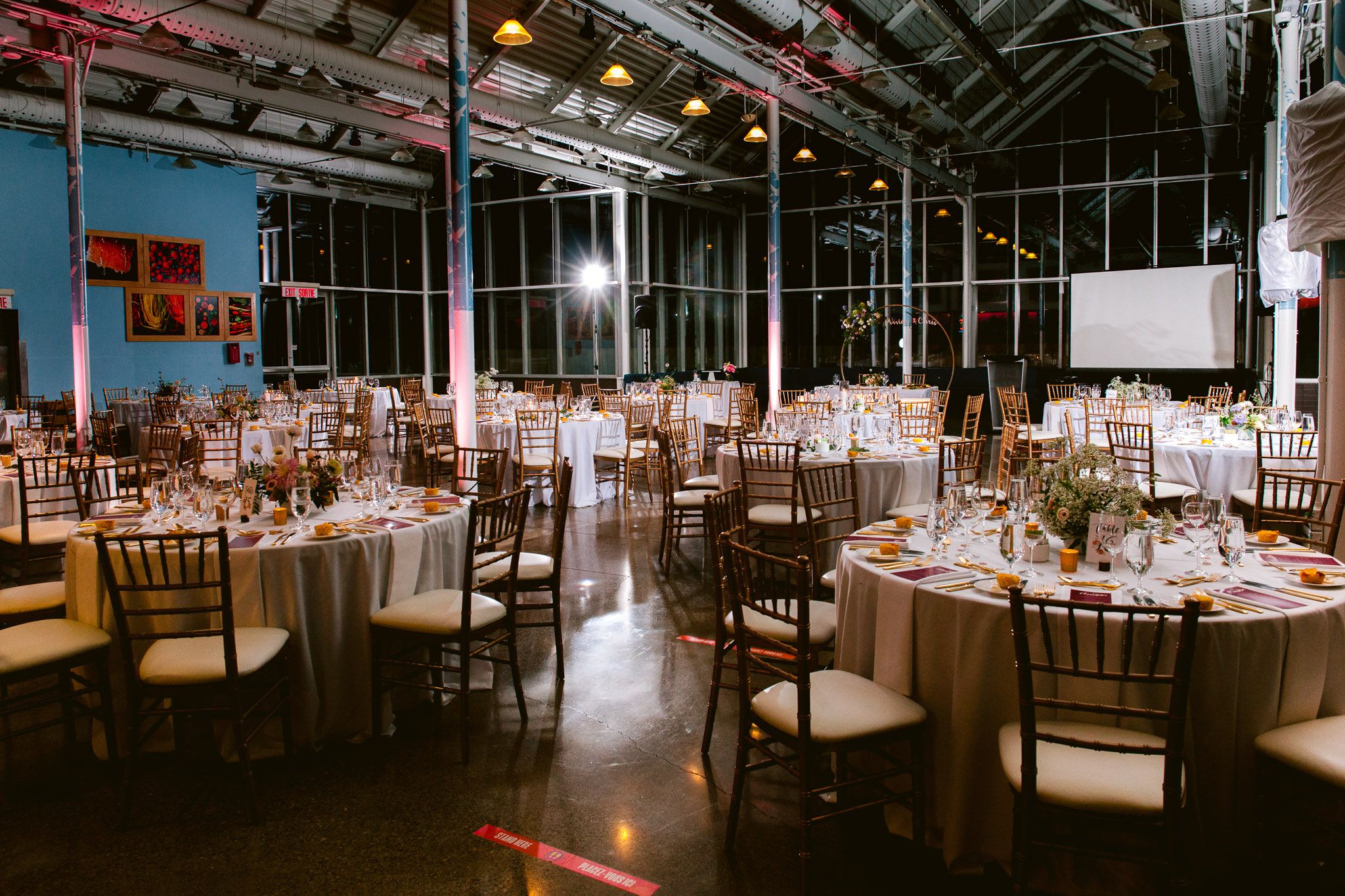 Elegant wedding reception hall with round tables and ambient lighting setup.
