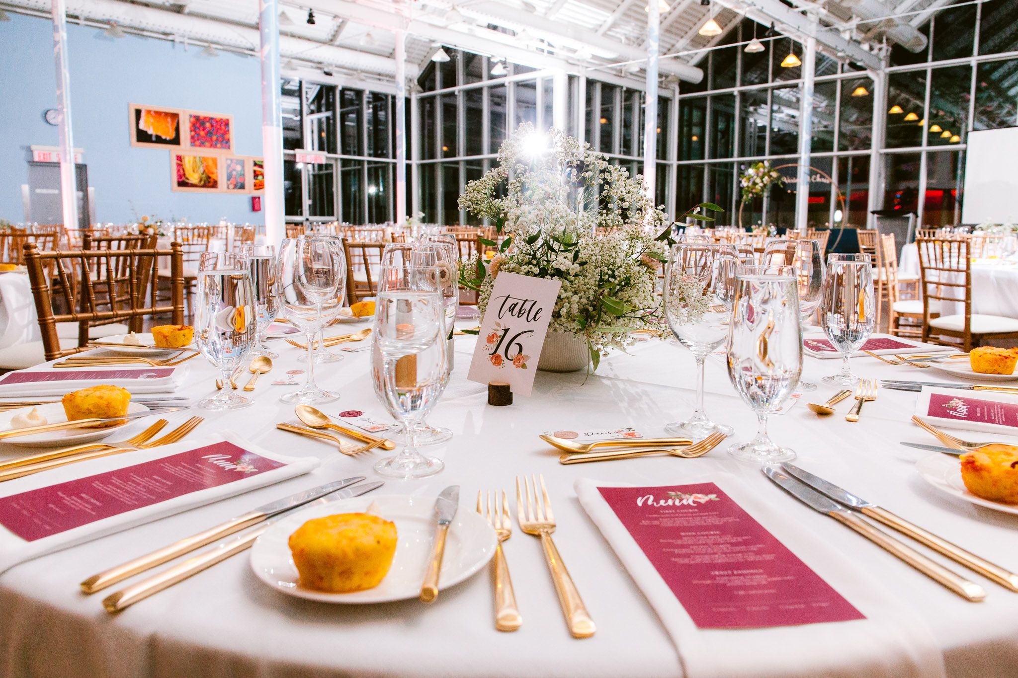 Elegant wedding reception table settings with burgundy accents and golden flatware.