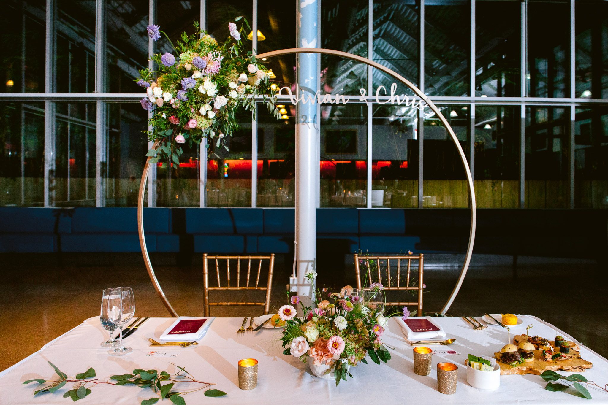 Elegant wedding reception table decorated with floral arrangements and place settings in a bright venue.